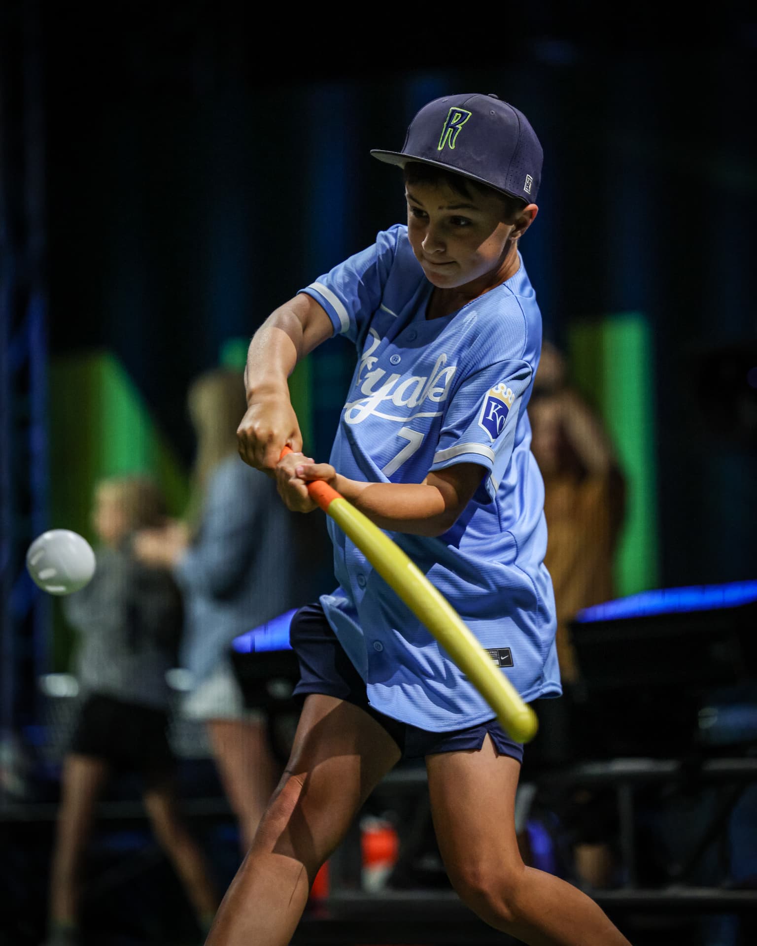A young hitter swinging under the lights