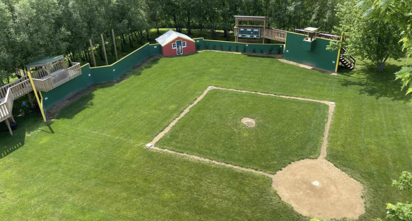A backyard Wiffle ball field with green outfield walls