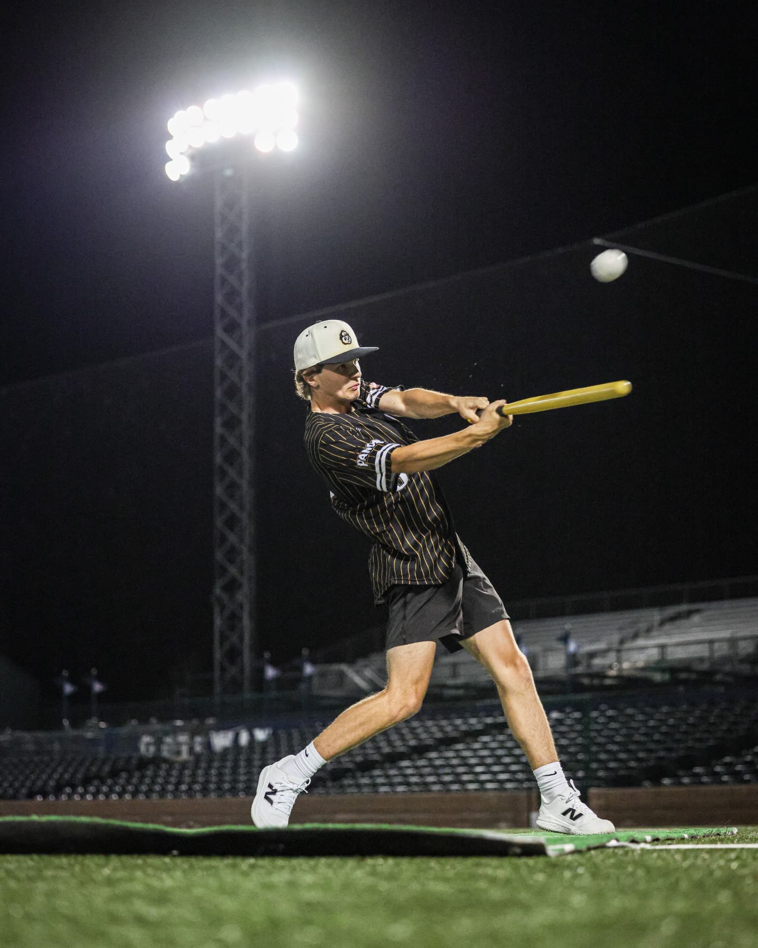 A hitter swinging under the stadium lights